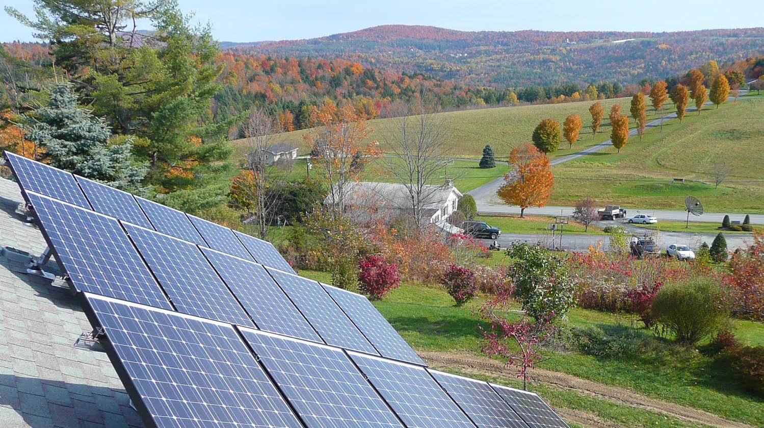 Solar panels on roof looking over open fields in the mountains of Vermont. Solar Panels were installed by Building Energy.