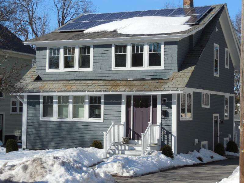 Two story house with snow covered solar panels on the roof